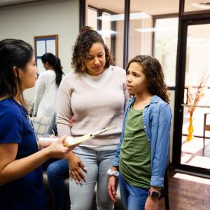 Young girl and mother talking to nurse
